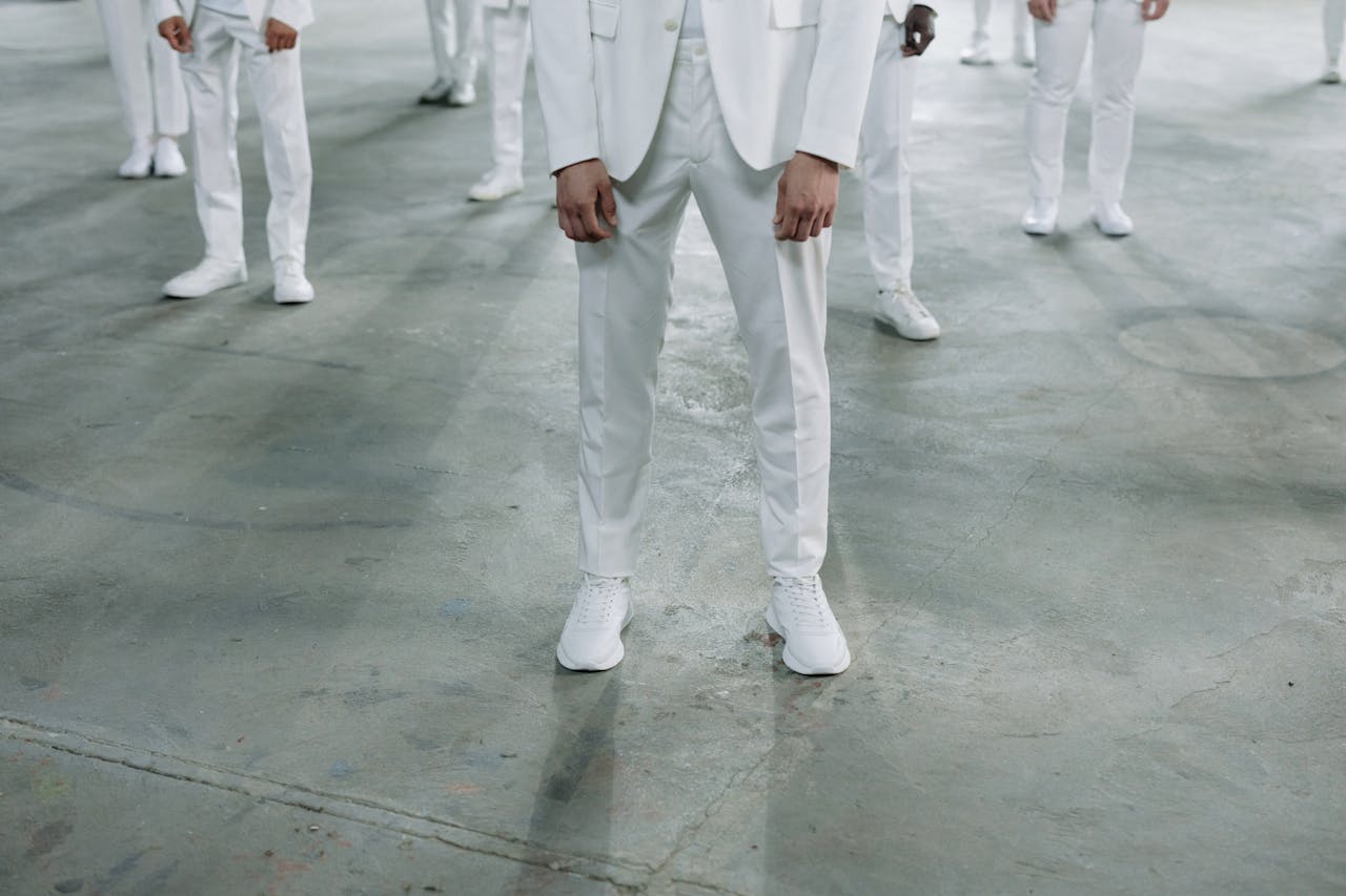 creative-03 Group of models in white suits standing indoors, showcasing fashion style in a minimalist setting.