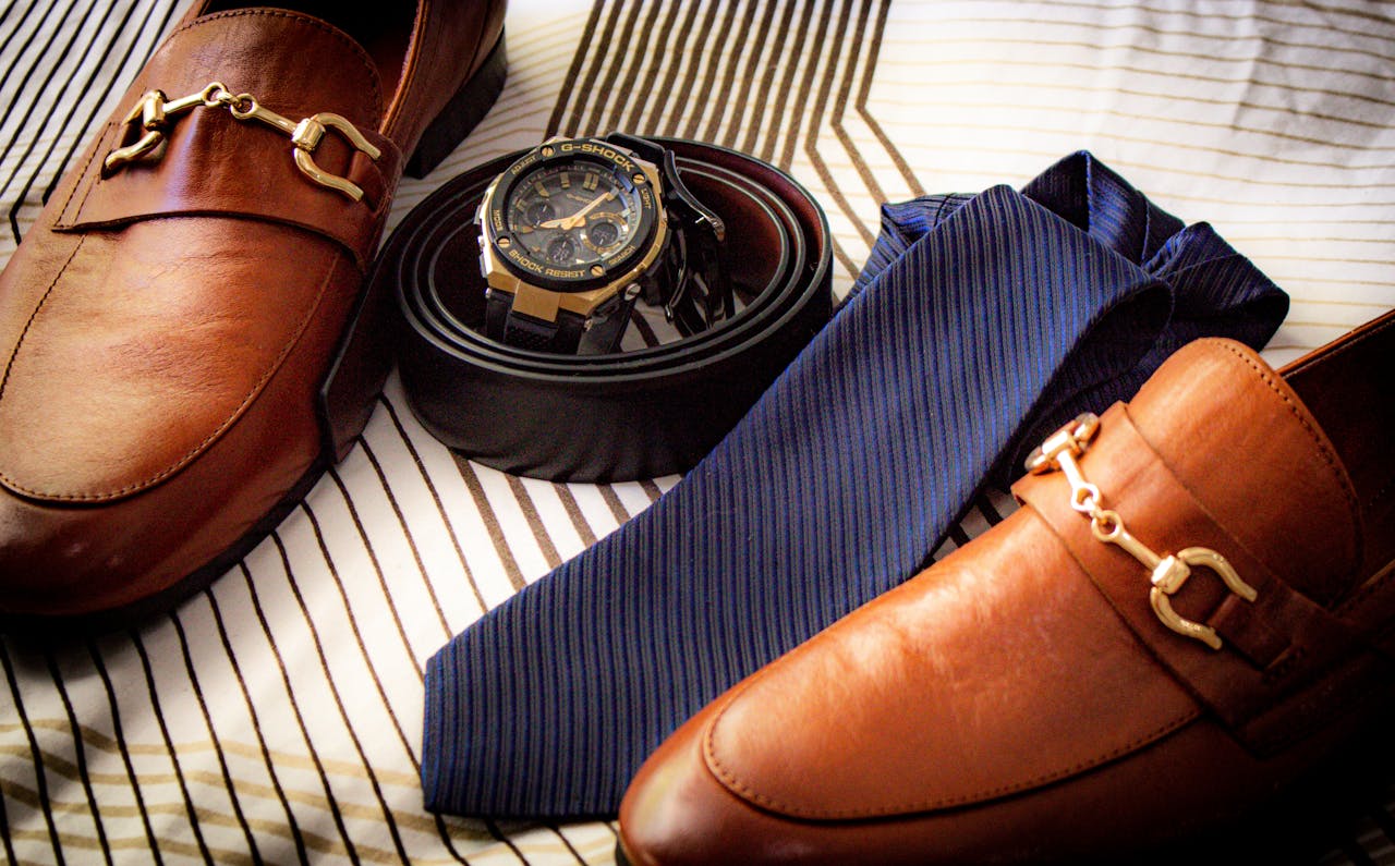 mobile-02 Close-up of elegant leather shoes, wristwatch, belt, and tie on striped fabric. Perfect for men's fashion.