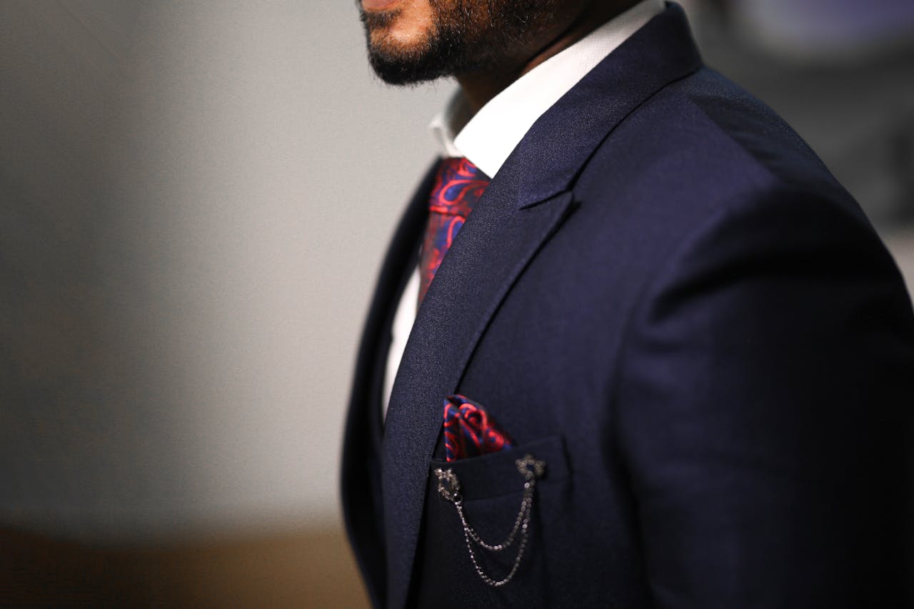 Close-up of a man in a navy suit with a stylish red tie and pocket square.