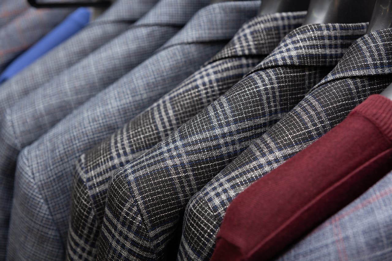 creative-03 A detailed view of classic men's suits in different patterns hanging in a wardrobe.
