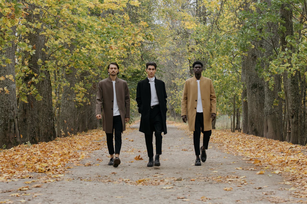 mobile-01 Three stylish men walking down a leaf-covered path in an autumn park.